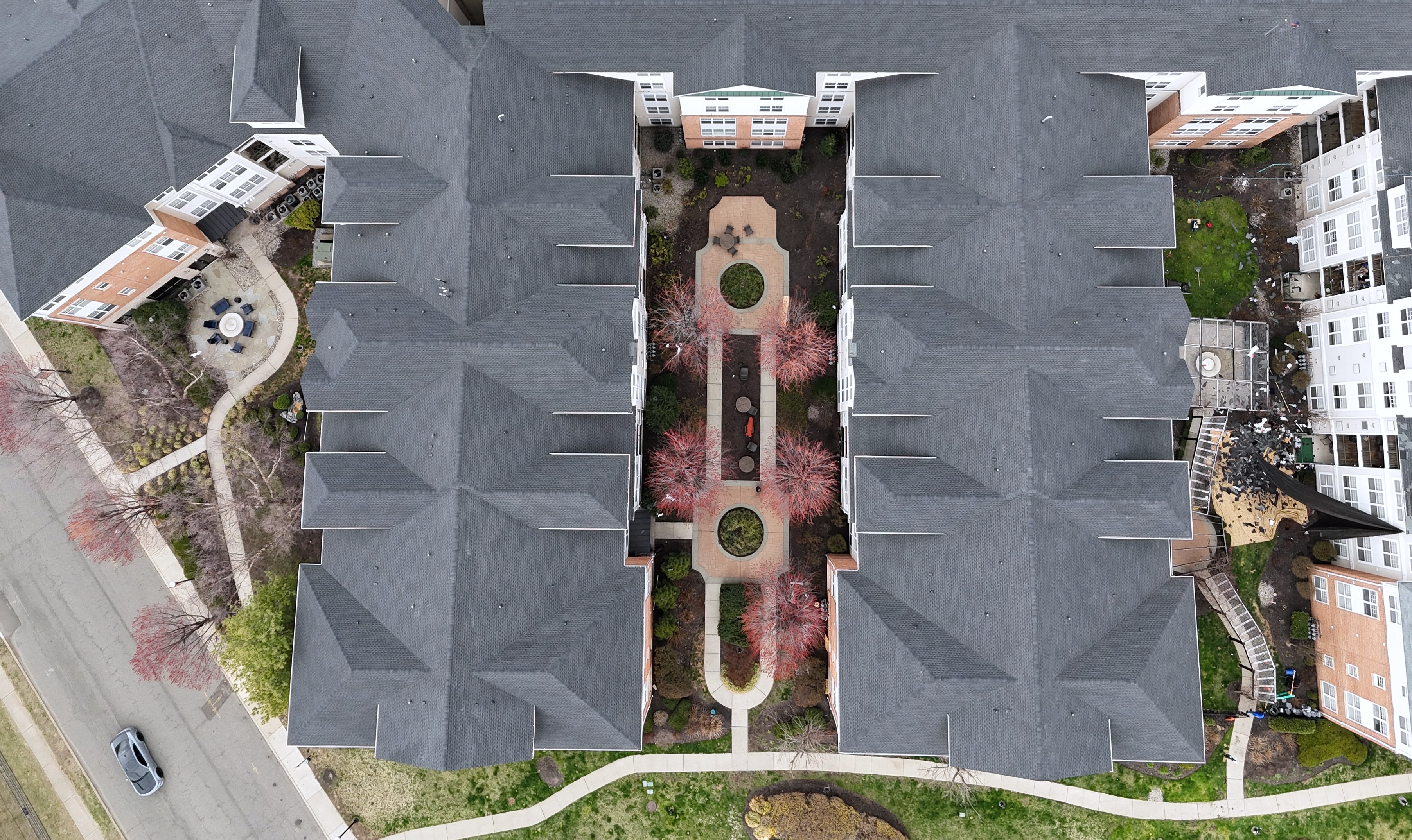 Top-down aerial of gray shingle roofs around courtyard